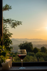 a glass of red wine stands in a window in Tuscany