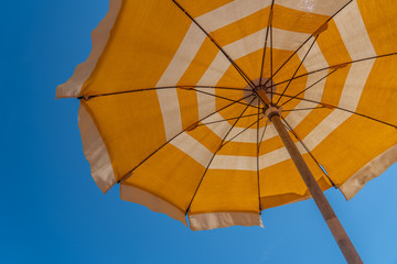 a bright yellow parasol stretched out on the beach