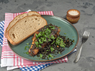 Fried sea bass with parsley.It's on a porcelain plate.On grey background