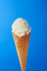 White ice cream in a waffle cone on a blue background. Close-up.