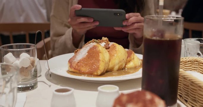 Woman take photo on cellphone with her souffle pancake in coffee shop