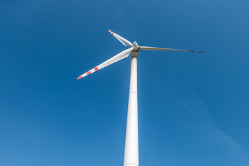 rotating blades of a windmill propeller on blue sky background. Wind power generation. Pure green energy.