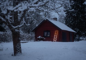 A cottage and a ladder with lights a winter afternoon in Sweden