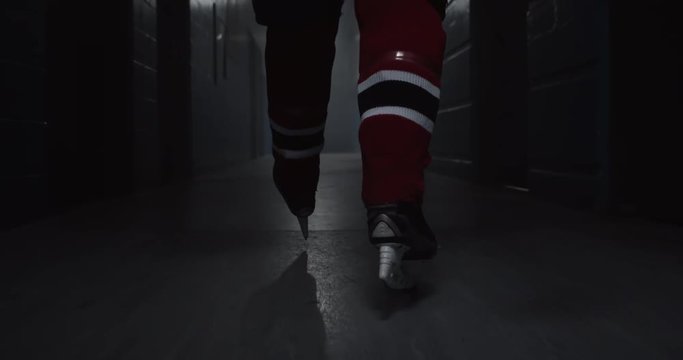 A hockey player walks down a hallway with intensity towards hockey arena featuring his hockey skates, building drama, 4K
