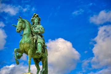 Fototapeta na wymiar Versailles, France - April 24, 2019: Louis XIV statue just outside of the gates of Versailles Palace on a sunny day outside of Paris, France.