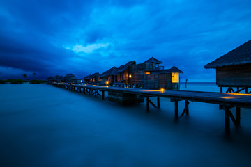 Water villa and wooden path of Luxury Maldives resort at sunrise