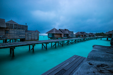 Water villa and wooden path of Luxury Maldives resort at sunrise