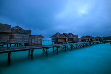 Water villa and wooden path of Luxury Maldives resort at sunrise