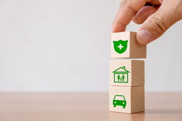 Insurance and investment concept of health, life, accident and travel..Hand picked wooden block with insurance sign and symbol of house, family, car