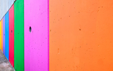 Colorful stripes painted on the wall, vertical, perspective, bold saturated colors.