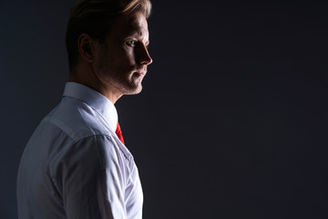 smart handsome caucasian businessman white shirt hand touch red neck tie ready to action pose grey background