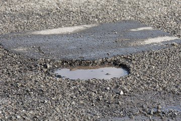 Fototapeta na wymiar pothole filled with water on an asphalt road