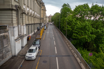 Beautiful scene of street with medieval buildings and fresh green trees in old town of Bern, Switzerland