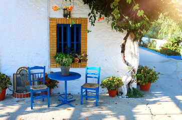 Fototapeta na wymiar landmark photo of blue chairs with table in typical Greek town