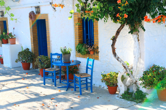 landmark photo of blue chairs with table in typical Greek town