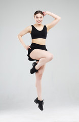 Sport, fitness and people concept: Beautiful young woman dressed in sportswear jumping up over grey background
