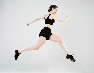 Sport, fitness and people concept: Beautiful young woman dressed in sportswear jumping up over grey background