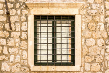Iron window on the facade of a stone house