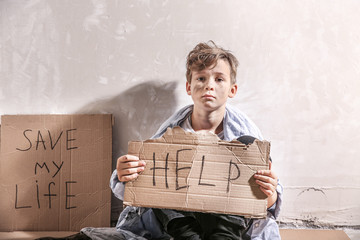 Homeless little boy begging for help indoors