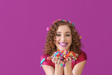 Happy young woman with confetti on color background