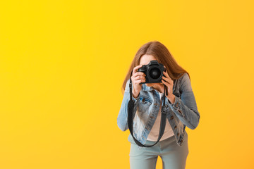 Young female photographer on color background