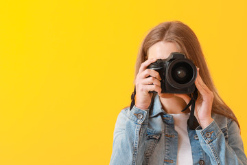 Young female photographer on color background