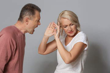 Quarrelling middle-aged couple on grey background