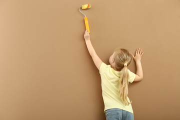 Little girl painting color wall