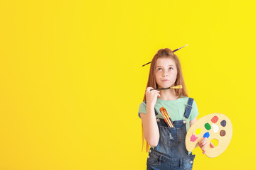 Thoughtful little artist on color background