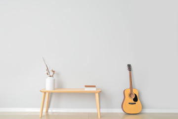 Table with guitar near light wall in room