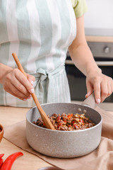 Woman cooking traditional chili con carne in kitchen, closeup
