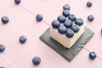 Tasty mousse cake with blueberry on color wooden background
