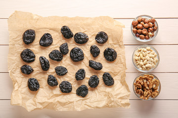 Tasty prunes with nuts on white wooden background