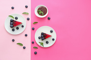 Pieces of tasty blueberry cheesecake on color background