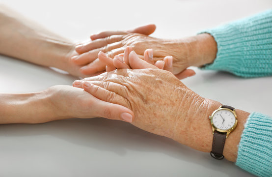 Hands of young and elderly woman on white background. Concept of support