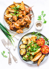 Meat skewers kebab with baked potatoes and roasted zucchini, tomatoes, cauliflower on a light background, top view. Delicious tapas, appetizers in mediterranean style