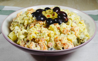 Russian salad dish typical Christmas dish, decorated with grapes cut in and green olives