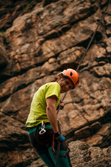 Close up portrait of a smiling man descending from the cliff against brown cracked rock