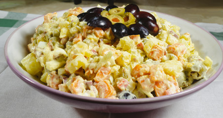 Russian salad dish typical Christmas dish, decorated with grapes cut in and green olives