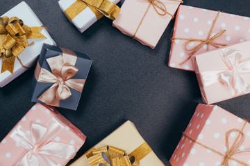 beautiful gift boxes wrapped in paper with red, gold and pink ribbon on a black surface. Top view...