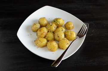 Roasted small potato tubers with spices on white plate