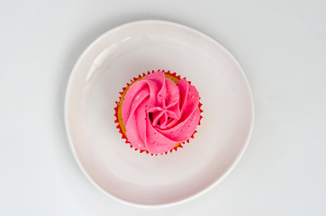 Pink cupcake on a plate isolated on white background. Delicious cake. Top view.