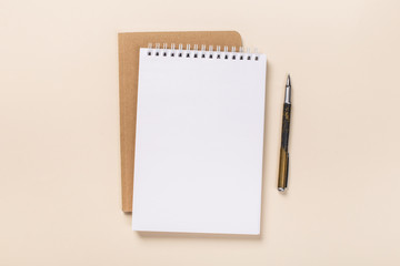 school notepad and pen on the beige desk. spiral notepad on a table. flatlay