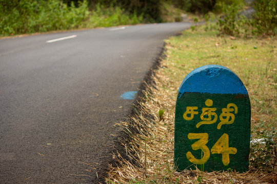 Beautiful Ghat road with Milestone indicating distance to Sathyamangalam (in tamil) along the mountain range of Talamalai Reserve Forest, Hasanur, Tamil Nadu - Karnataka State border, India