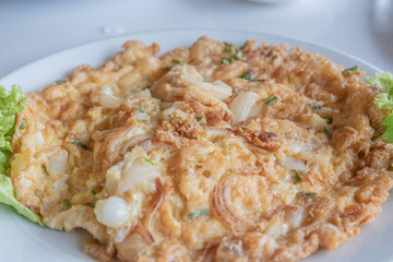 Close up of Thai omelet on white dish.