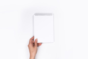 Woman's hands with perfect manicure holding  notepad as mockup for your design. White background, flat lay style.