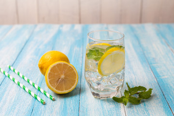Fresh lemonade with lemon in glass on wooden background