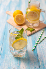 Fresh lemonade with lemon in glass on wooden background