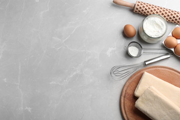 Puff pastry dough and ingredients on grey table, flat lay. Space for text