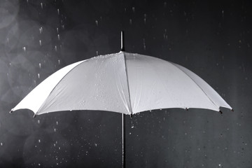 White umbrella under rain on dark background